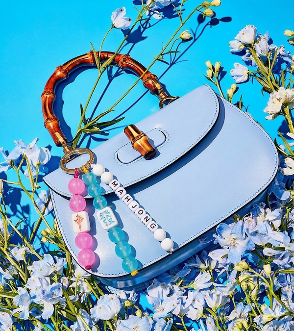 Light blue handbag with a keychain on a blue background with flowers