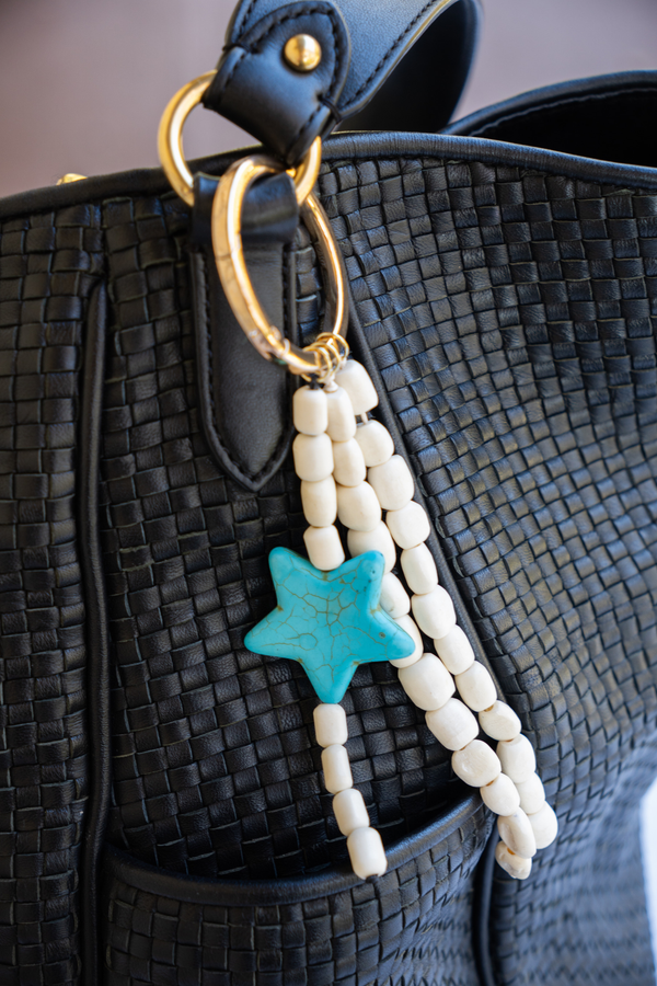 Beaded keychain with a blue star charm attached to a black textured bag.