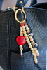 Beaded keychain with heart charm attached to a black textured bag.