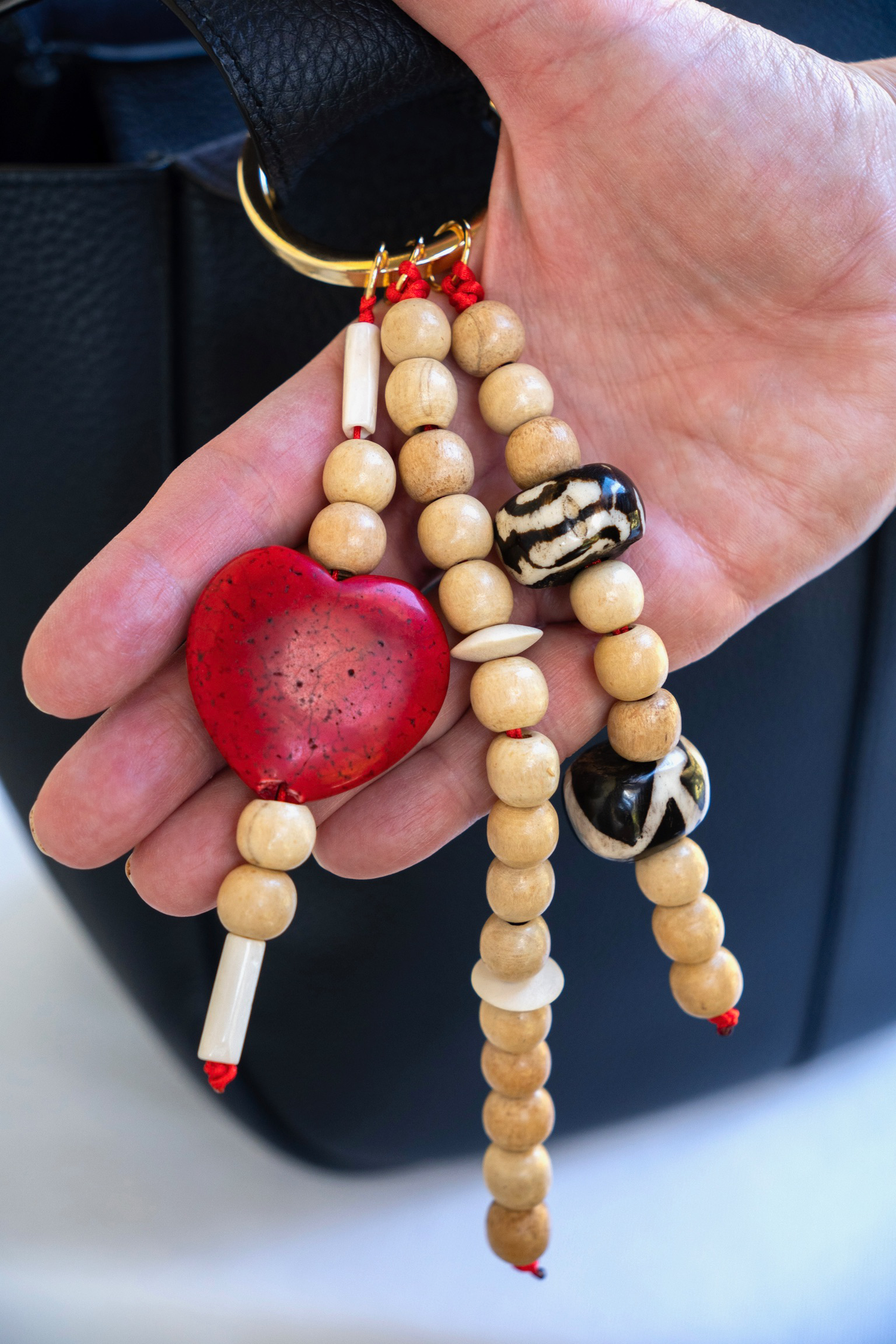 Hand holding a keychain with wooden beads and decorative elements