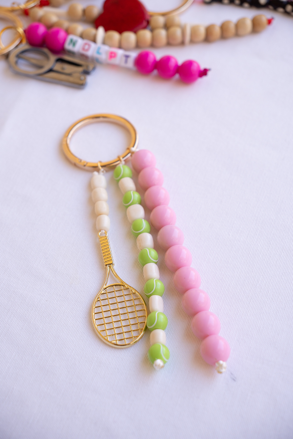 Beaded keychain with tennis racket charm on a white background