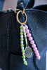 Beaded keychain with a tennis racket charm attached to a black handbag.