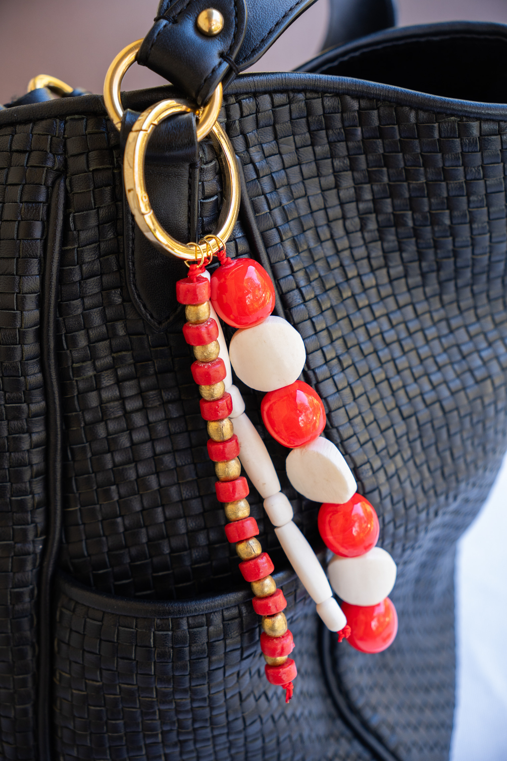Beaded keychain with red and white beads attached to a black textured bag.
