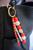 Beaded keychain with red and white beads attached to a black textured bag.