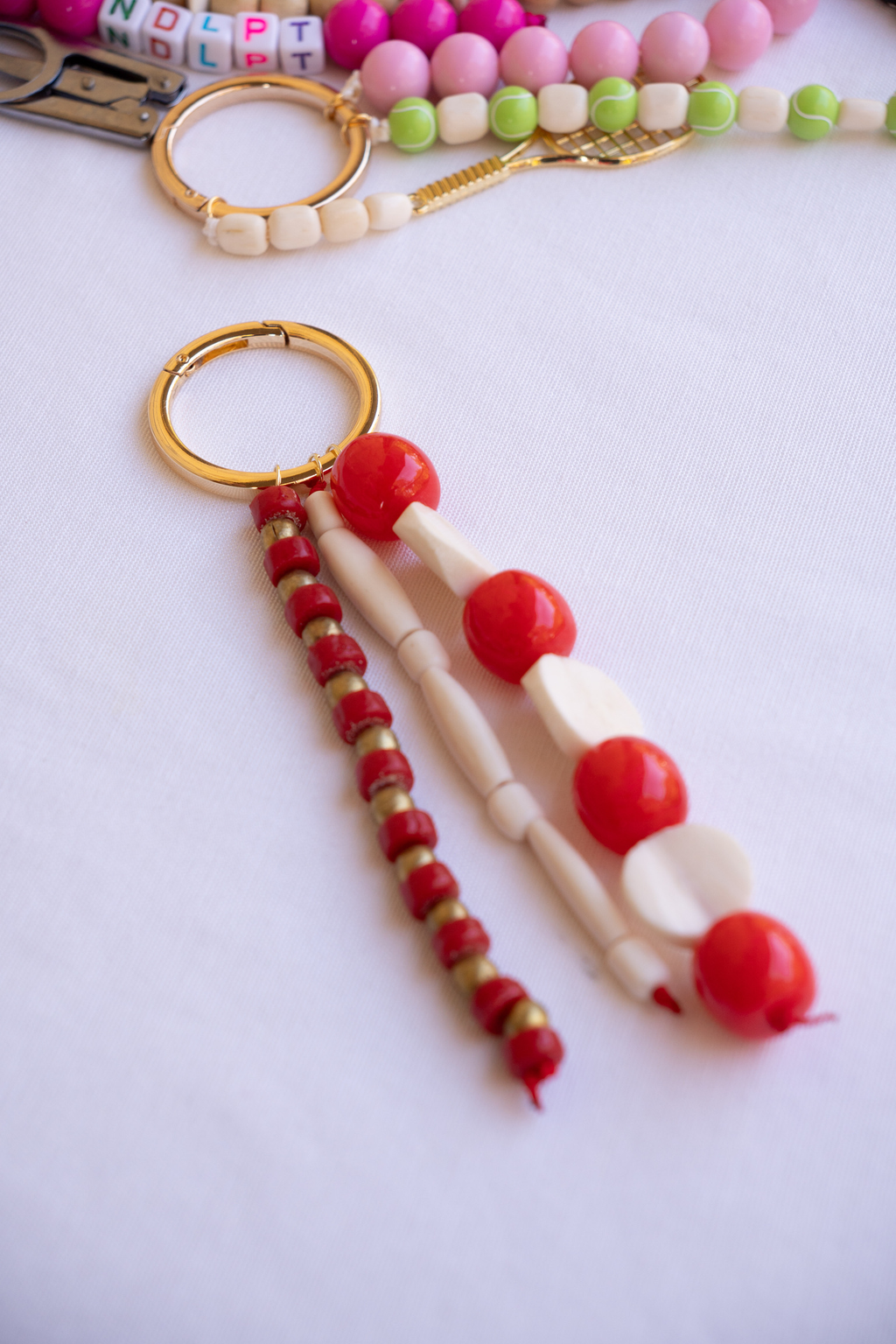 Beaded keychain with red, white, and gold beads on a light background