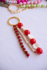 Beaded keychain with red, white, and gold beads on a light background