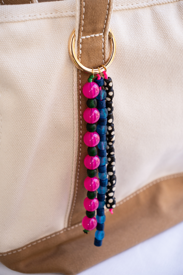 Colorful beaded keychain attached to a beige bag.