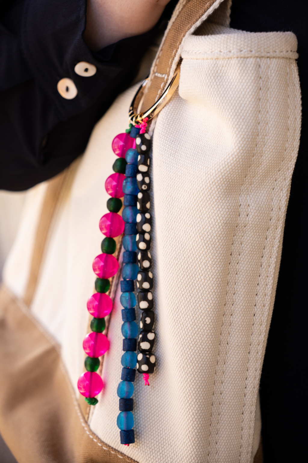 Colorful beaded keychains attached to a beige bag.