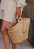 Person holding a woven basket with a decorative fish charm.