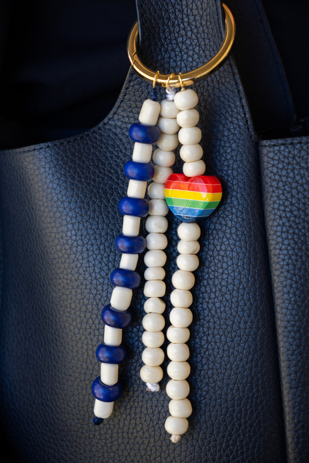 Beaded keychain with rainbow heart charm on a dark surface