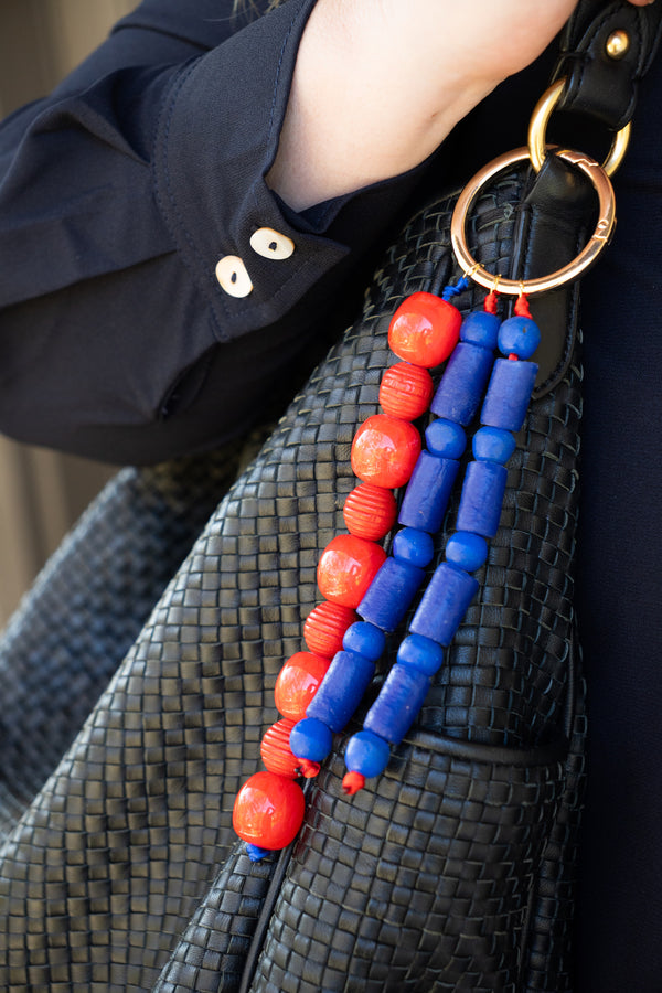 Black textured handbag with red and blue beaded strap detail