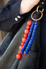 Black textured handbag with red and blue beaded strap detail