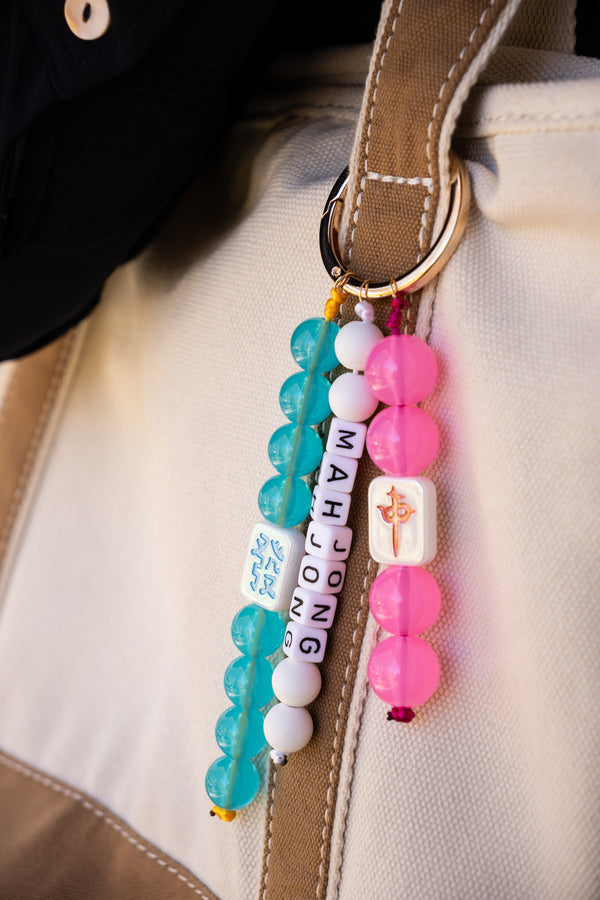 Colorful beaded keychain with 'Mah Jong' on a beige bag.