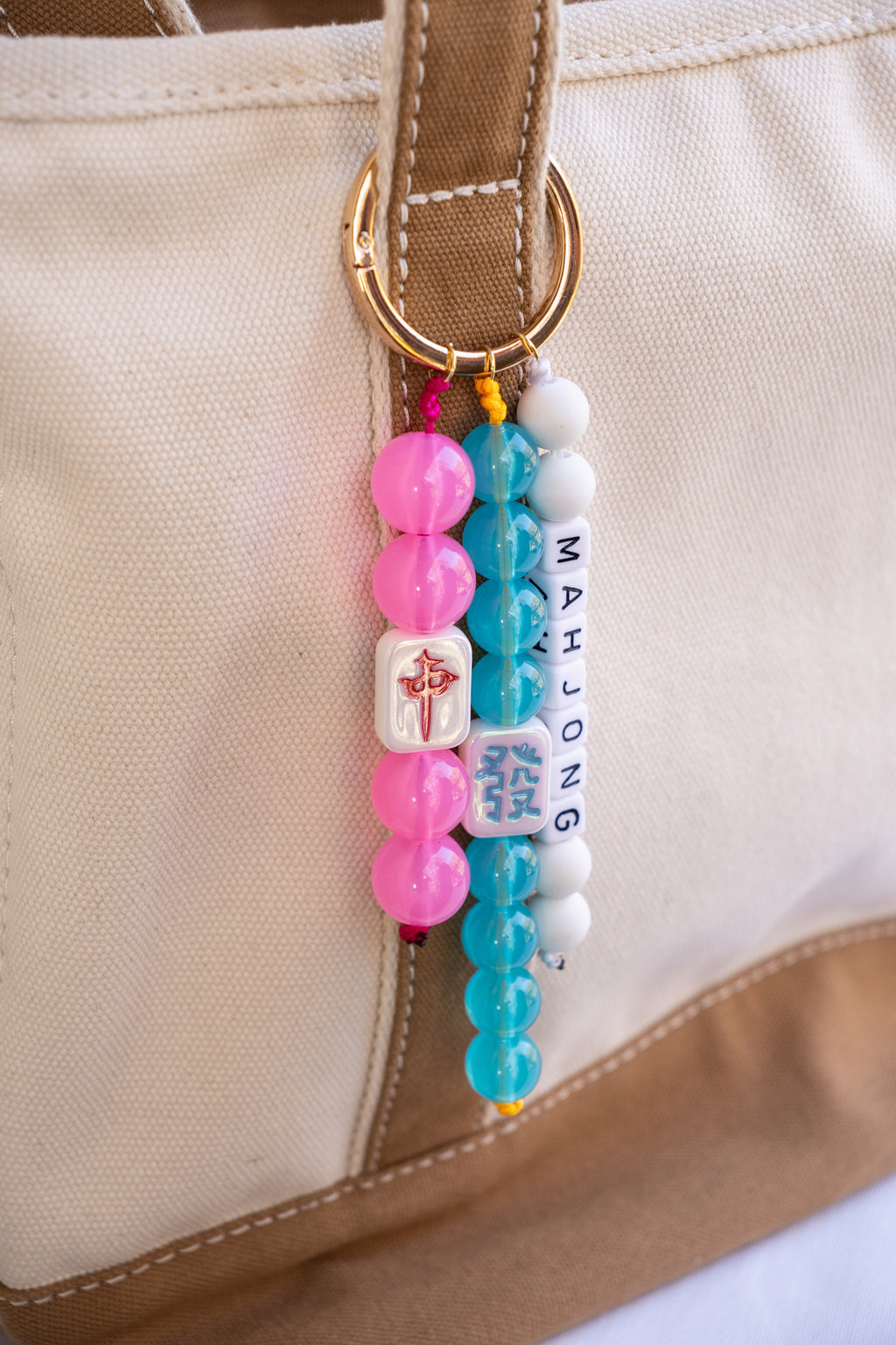 Colorful beaded keychain with 'Mahjong' on a beige bag.