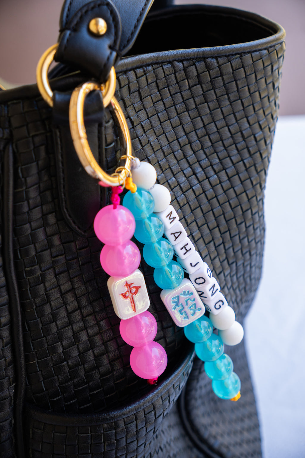 Colorful beaded keychain with 'Mahjong' text attached to a black woven bag.