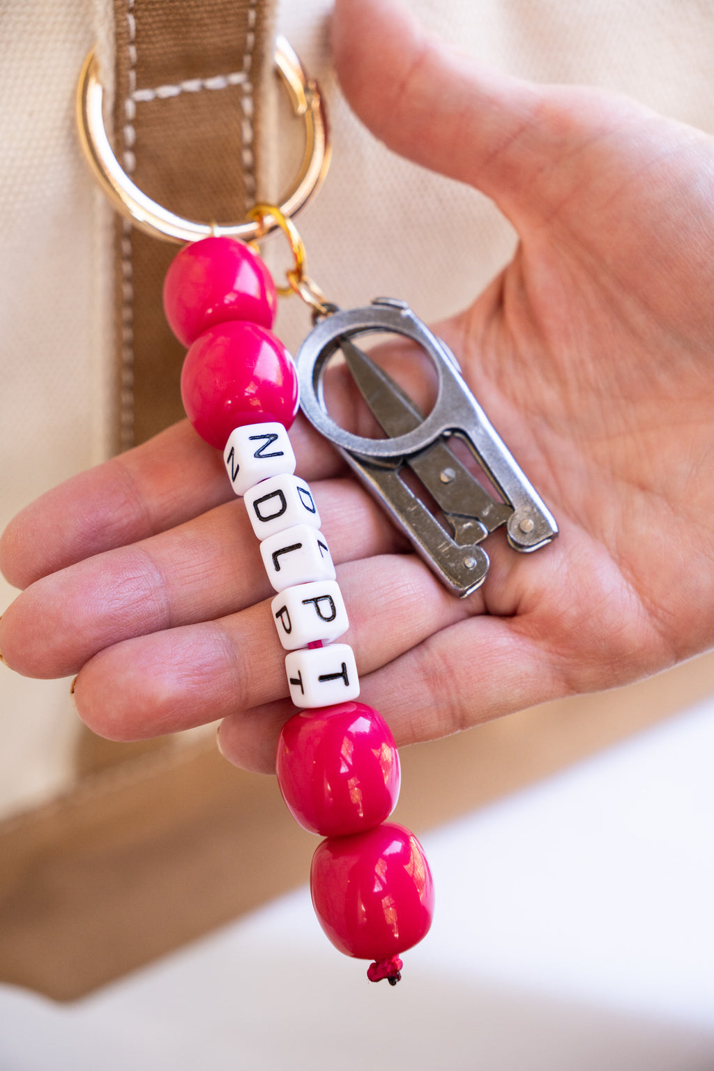 Bag Charm with pink beads and a bottle opener held by a hand