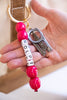 Bag Charm with pink beads and a bottle opener held by a hand